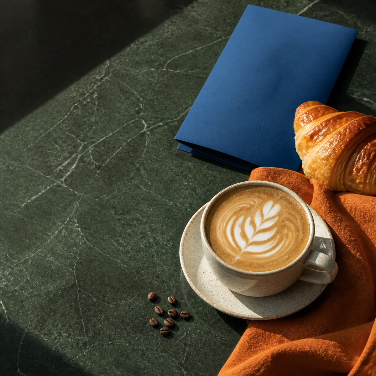 Cappuccino en croissant op een donkergroene tafel voor een social post