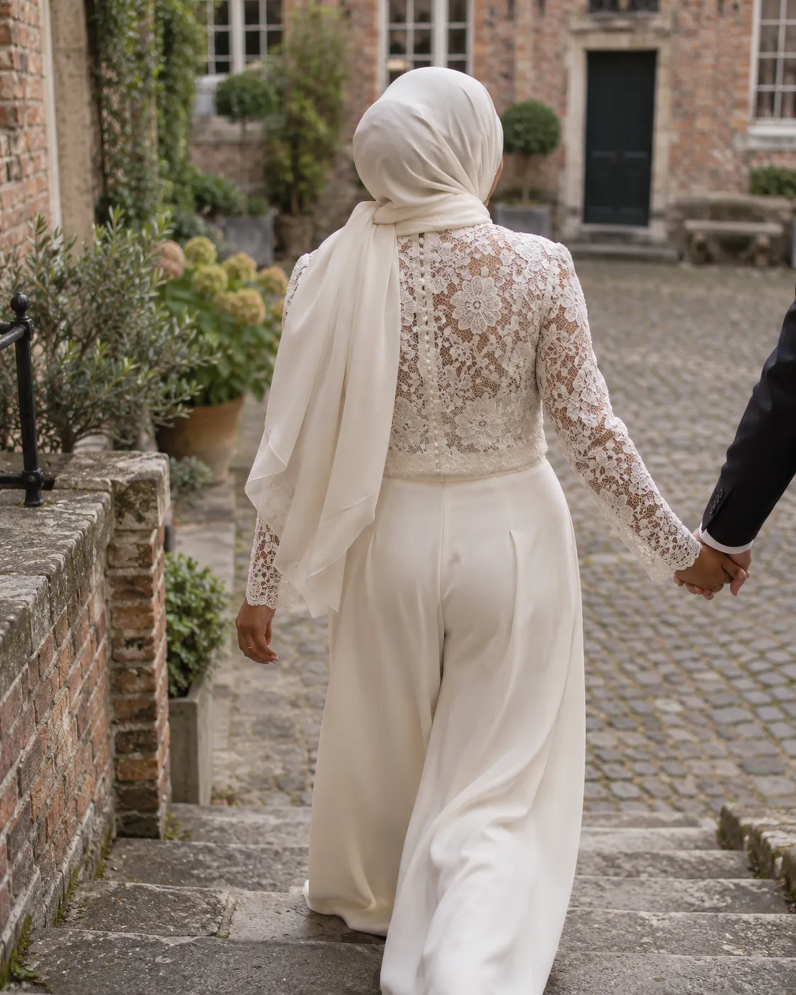 Fatima loopt de stenen trap van een binnenplaats af, in een kanten top met een wijde broek van crêpe (voorbeeld)
