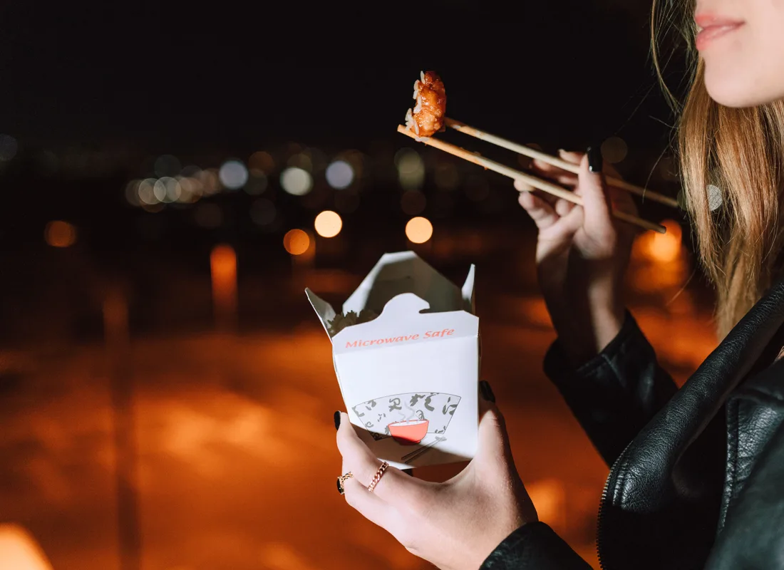 Iemand eet uit een afhaalbakje in de avond