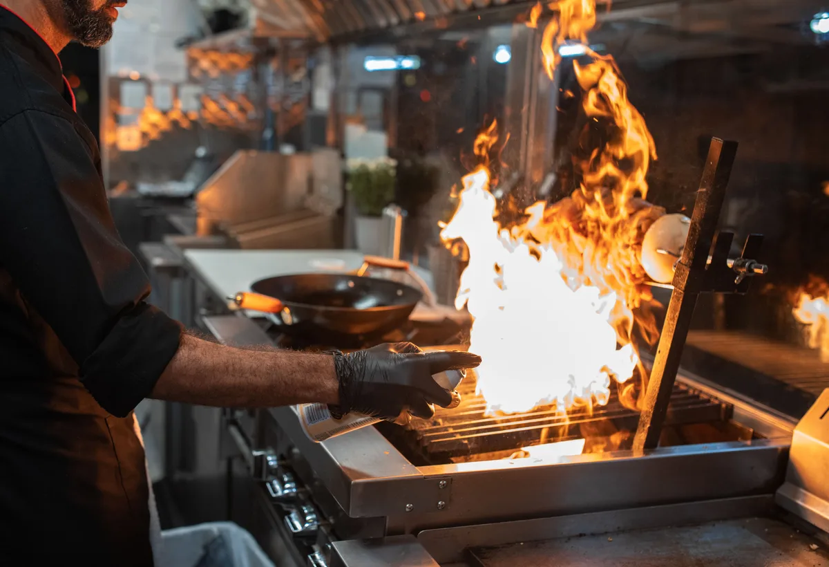 Chef wokt met hoge vlammen in Aziatische professionele keuken