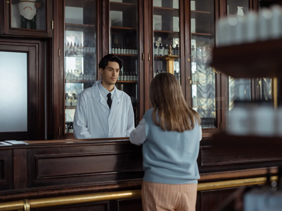 Apotheker helpt een klant aan de houten toonbank
