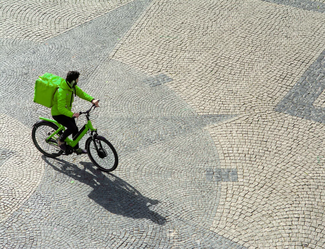 Bezorger op de fiets met een groene tas in de stad