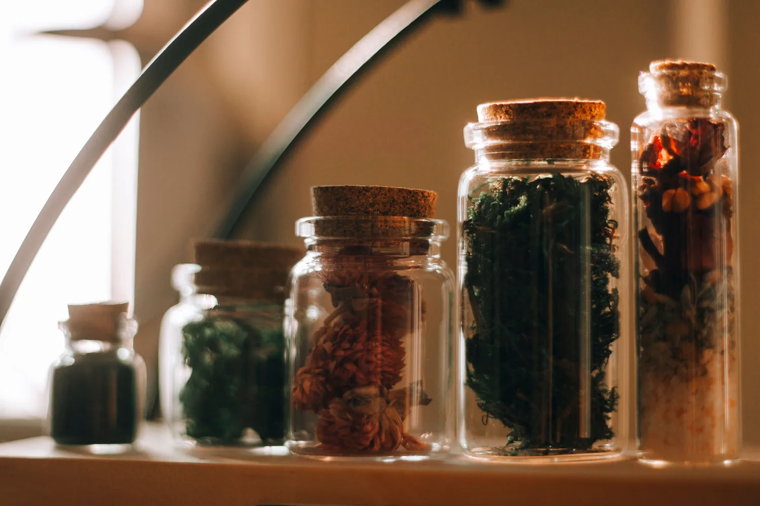Glazen apothekerspotten met gedroogde kruiden in warm licht