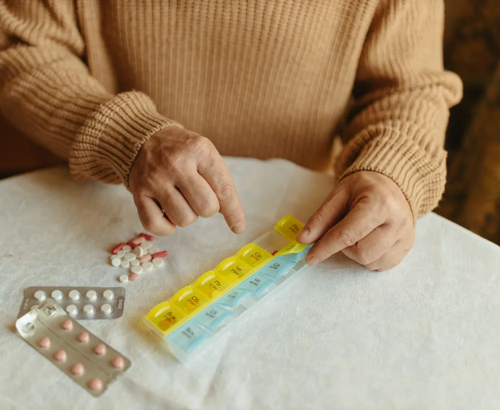 Iemand vult een weekdoos met medicijnen