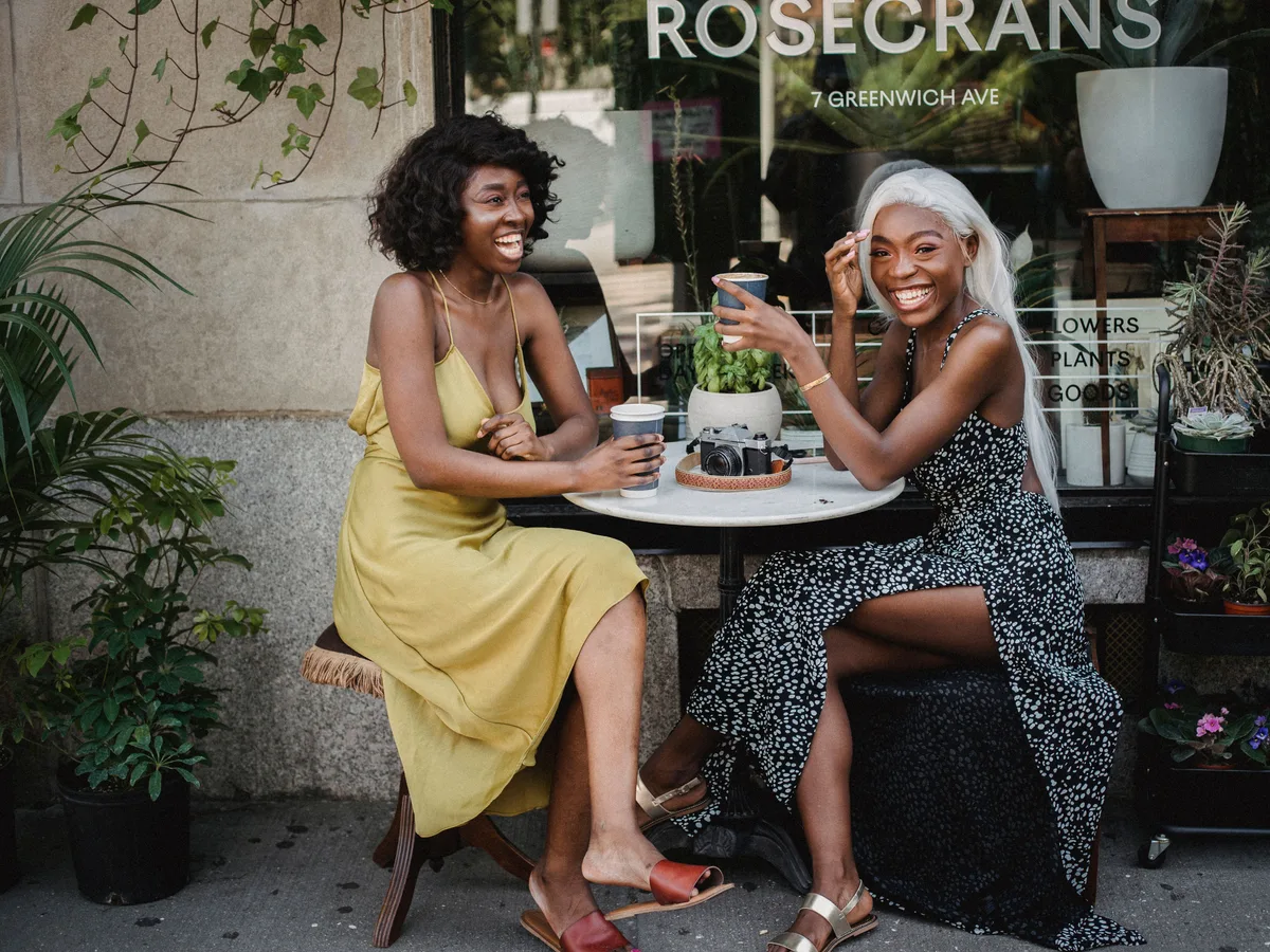 Twee vriendinnen lachen samen aan een cafétafeltje