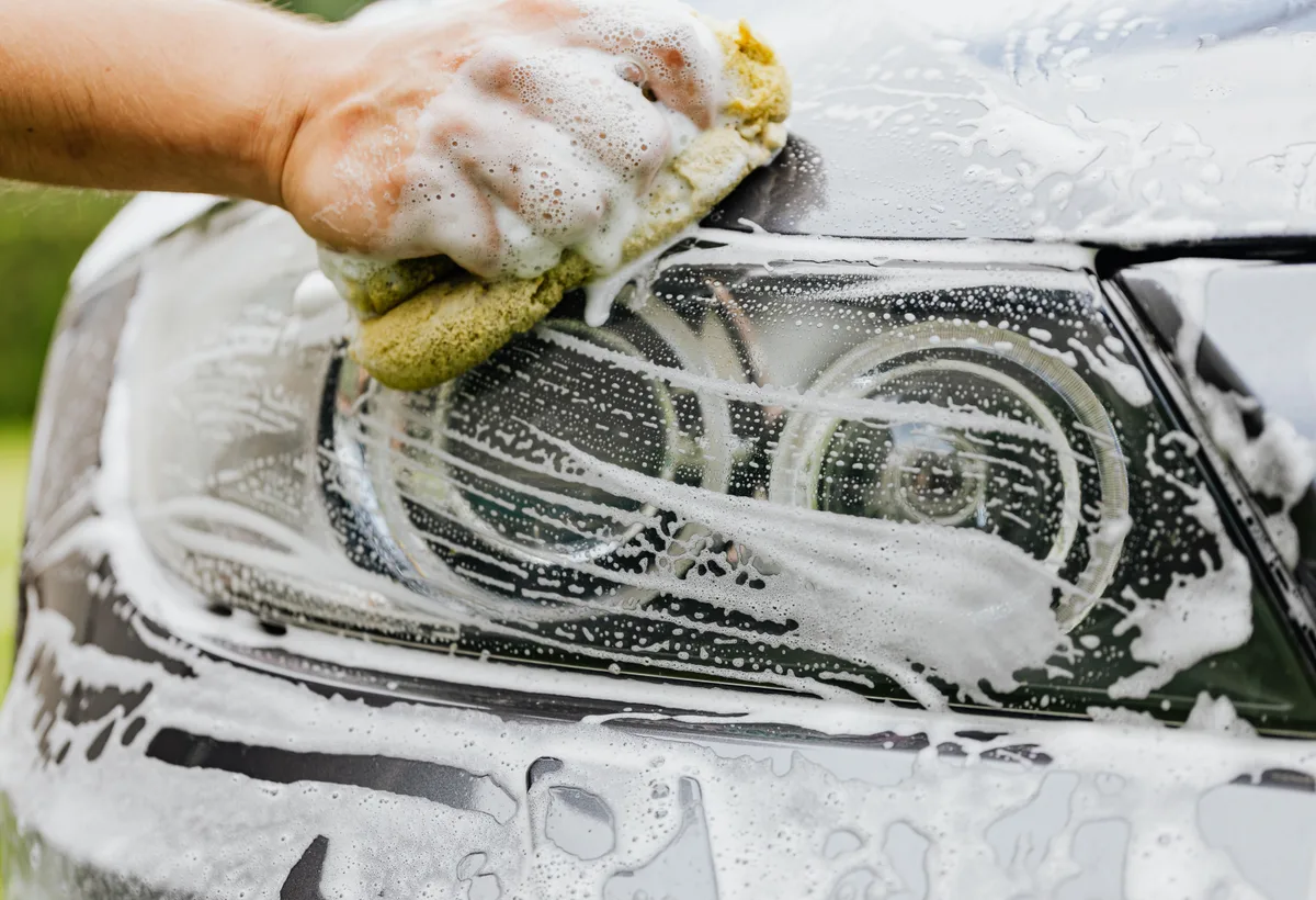 Schuimende snow foam voorwas op een sportwagen