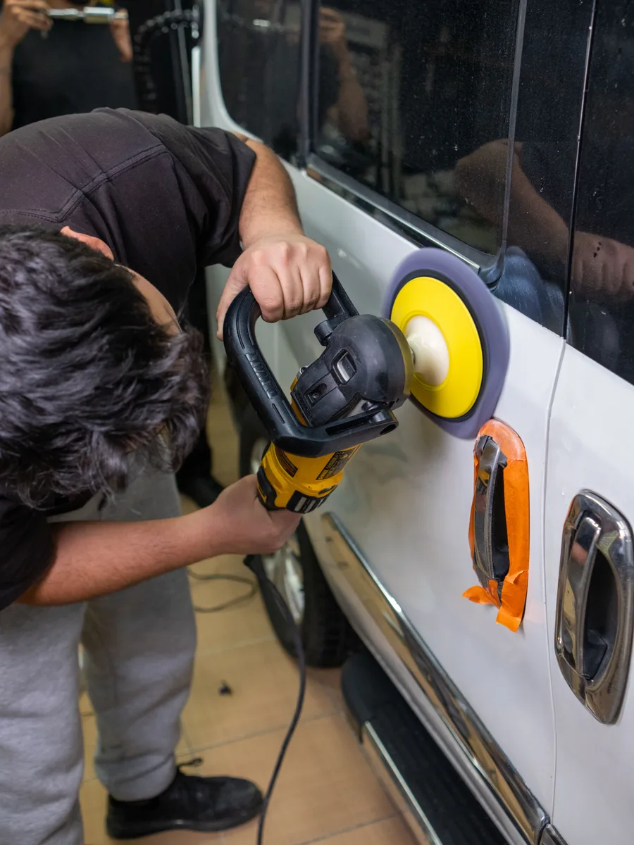 Detailer polijst lakwerk in het atelier