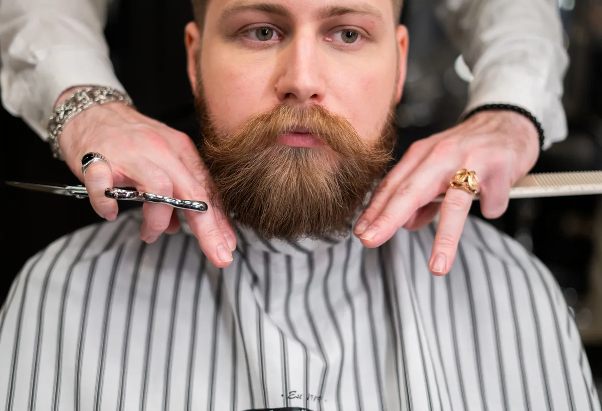 Barbier brengt verzorgende baardolie aan bij klant