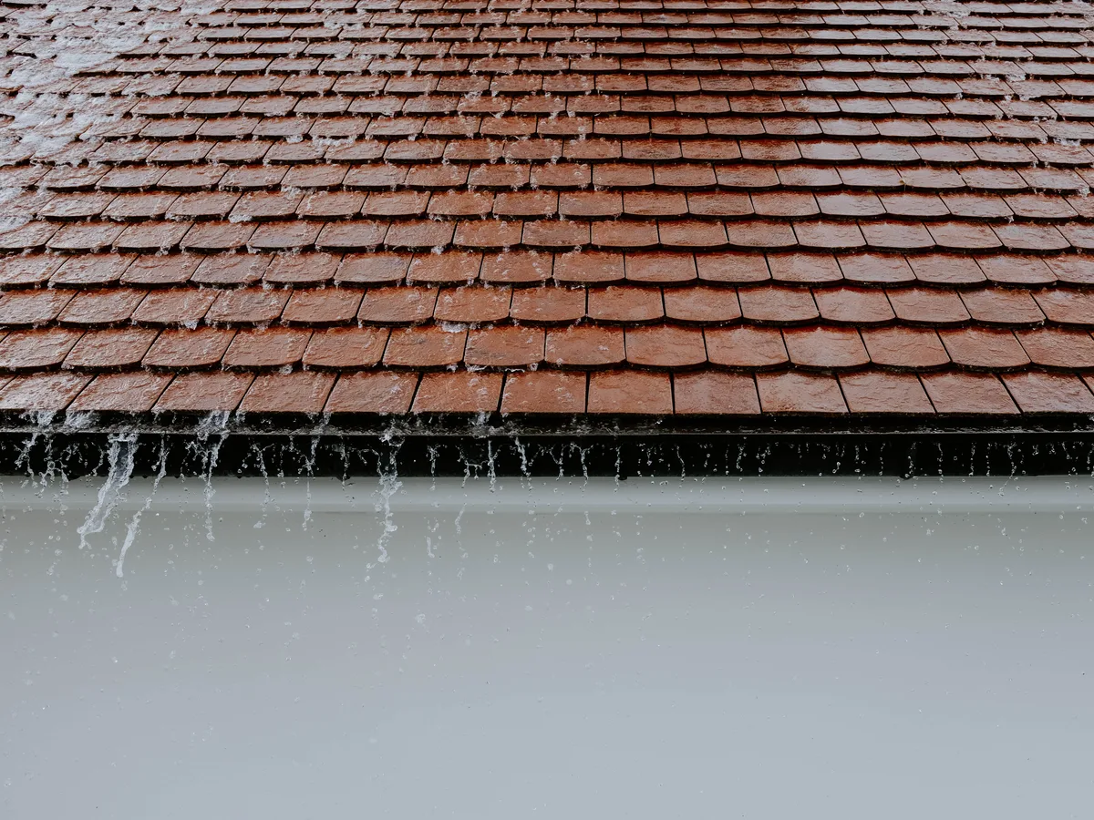 Regenwater stroomt over een dakgoot heen