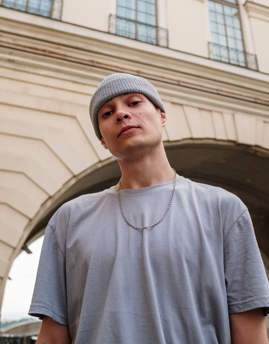 Jayden met beanie kijkt recht in de camera voor een stadsboog