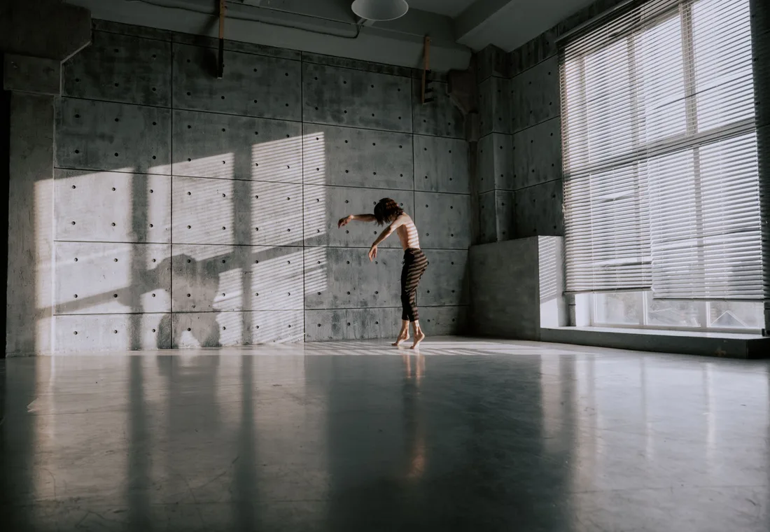 Danser in een betonnen studio, gestrekt op blote voeten in het strijklicht