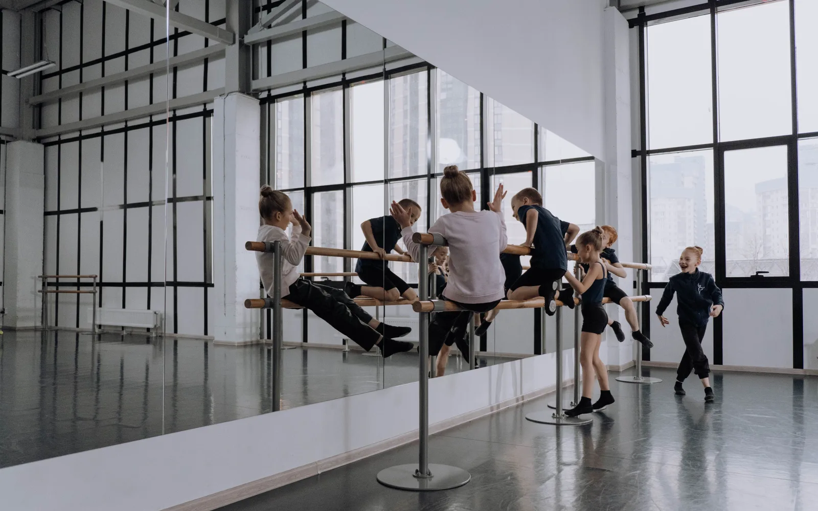 De spiegelzaal van PULS met barres, hoge ramen en een kidsles in beweging