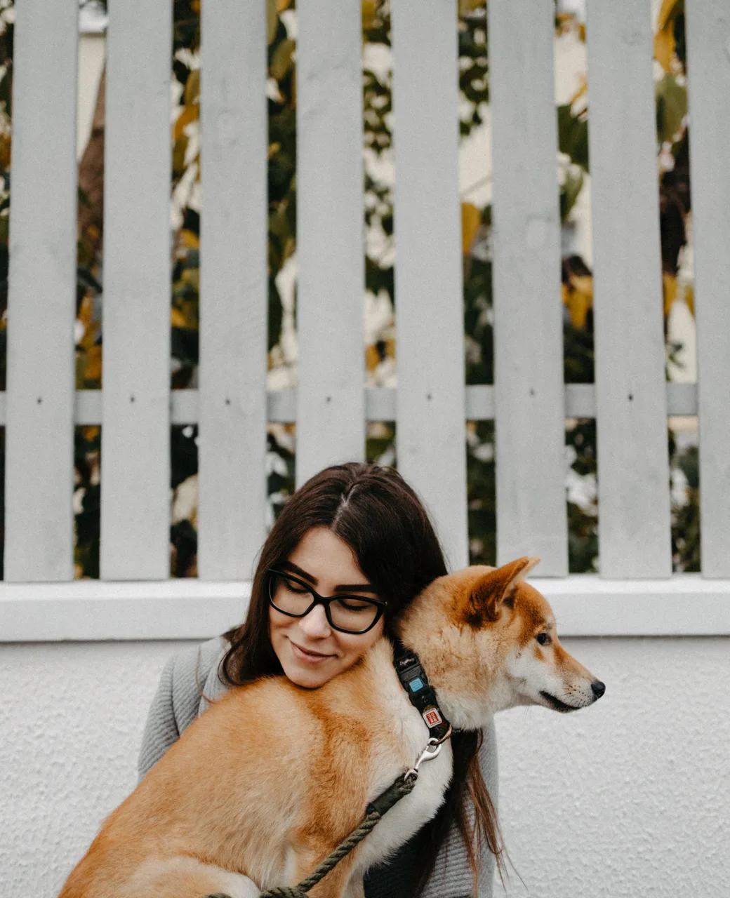 Vrouw met bril leunt liefdevol tegen haar hond