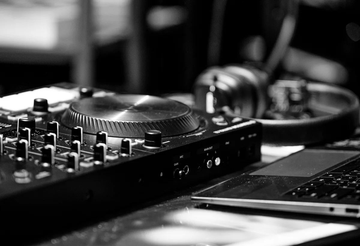 Koptelefoon rust op DJ mixer met playlist op scherm