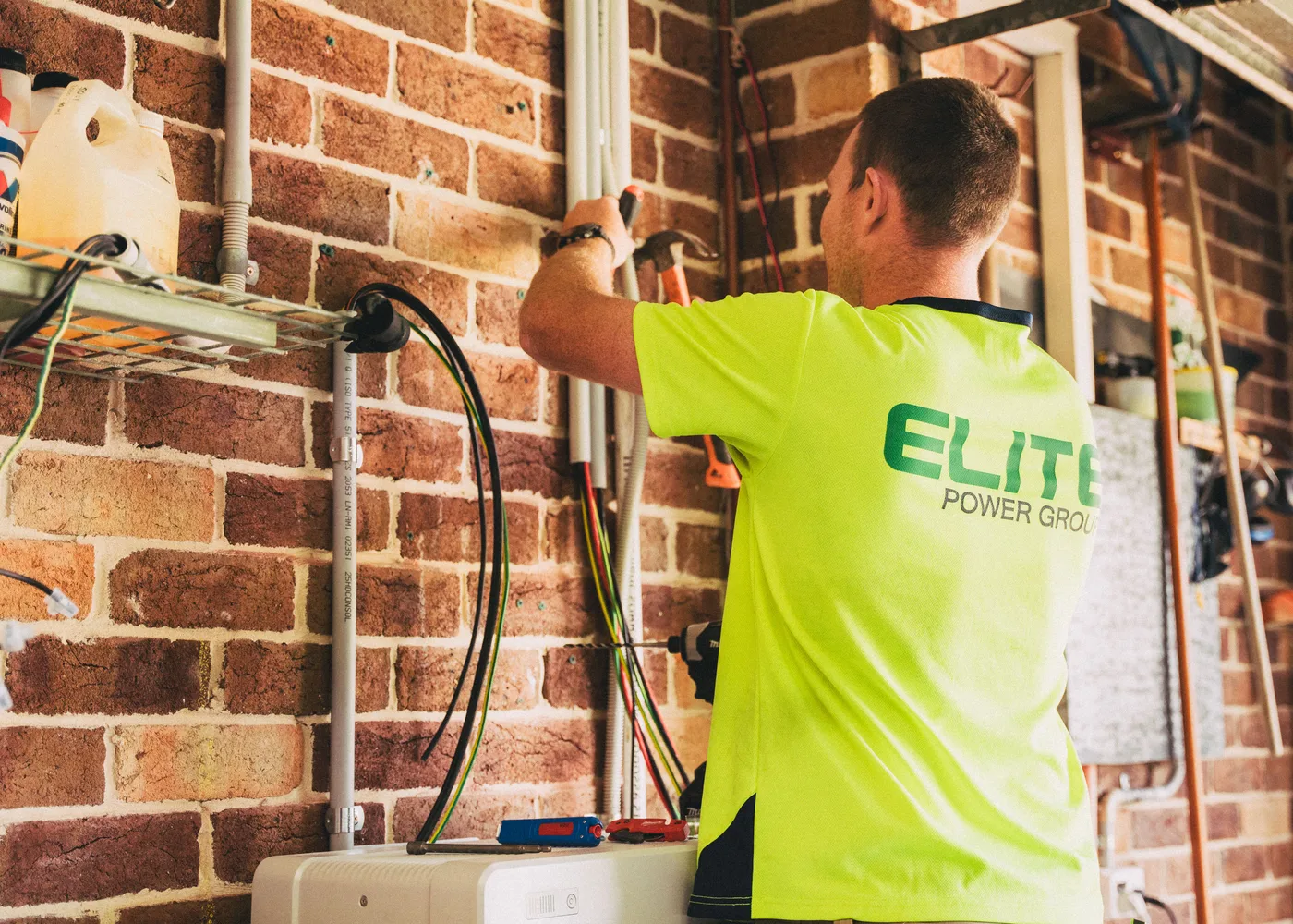 Monteur van Elite Power Group monteert een kabelgoot op een bakstenen wand