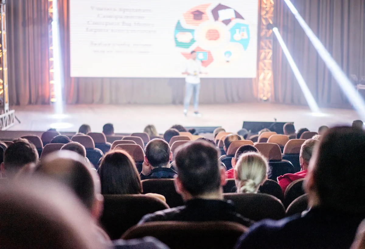Grote plenaire zaal met professioneel podiumlicht en publiek