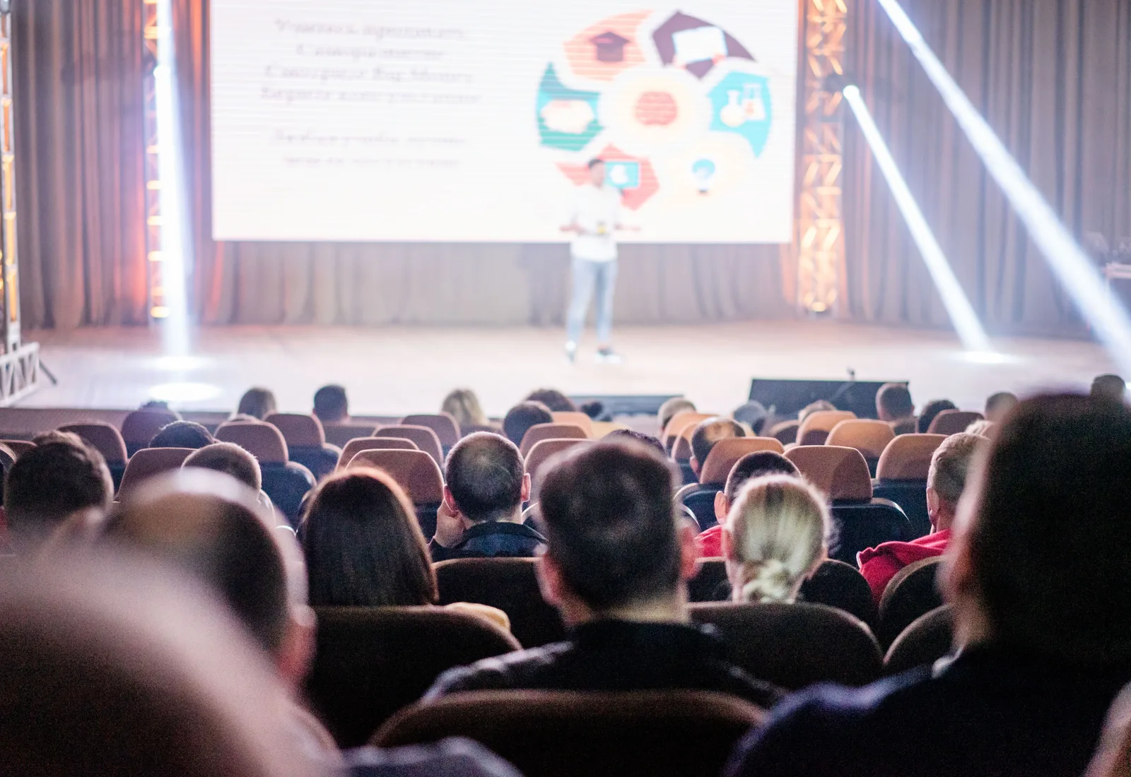 Publiek in een congreszaal bij een spreker op het podium