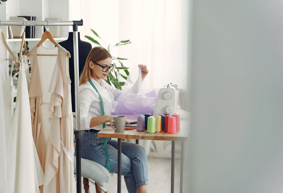 Coupeuse naait met precisie aan een wollen mantel in atelier