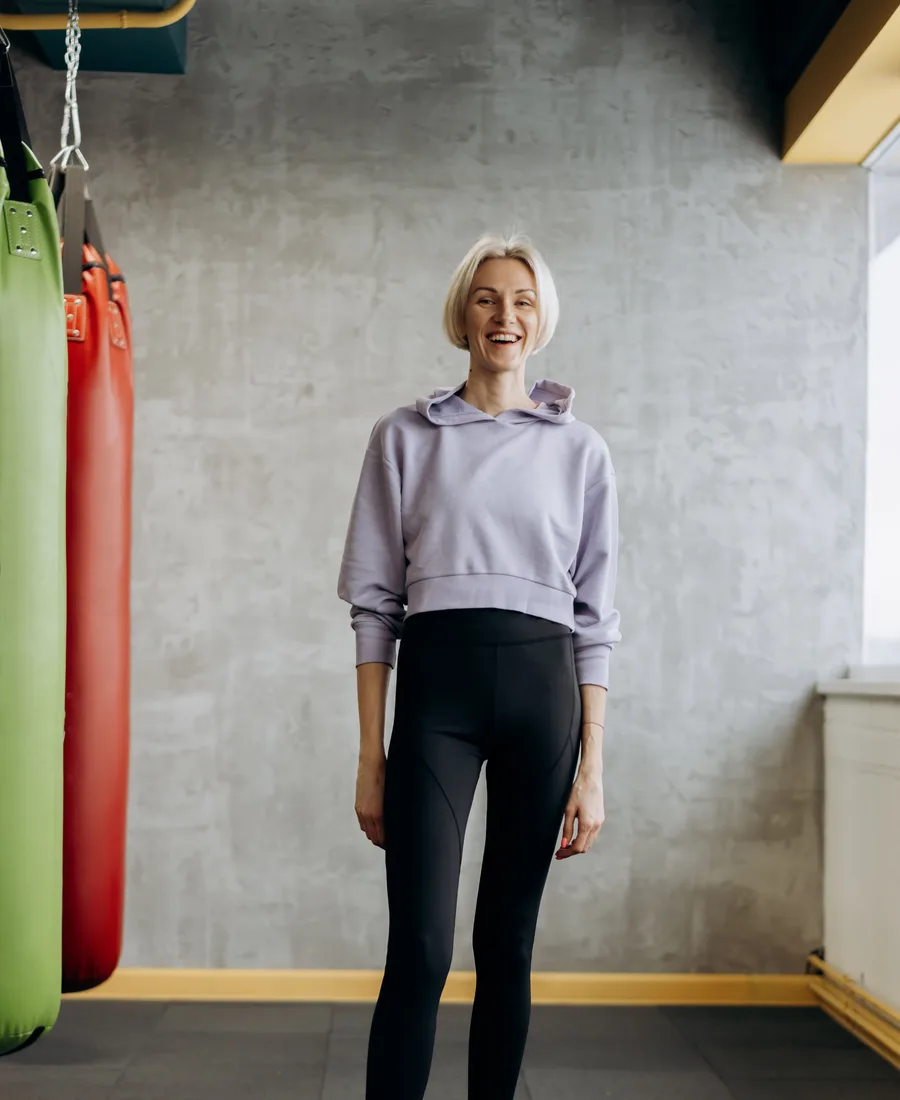 Coach Sanne lacht in de lichte studio bij het raam