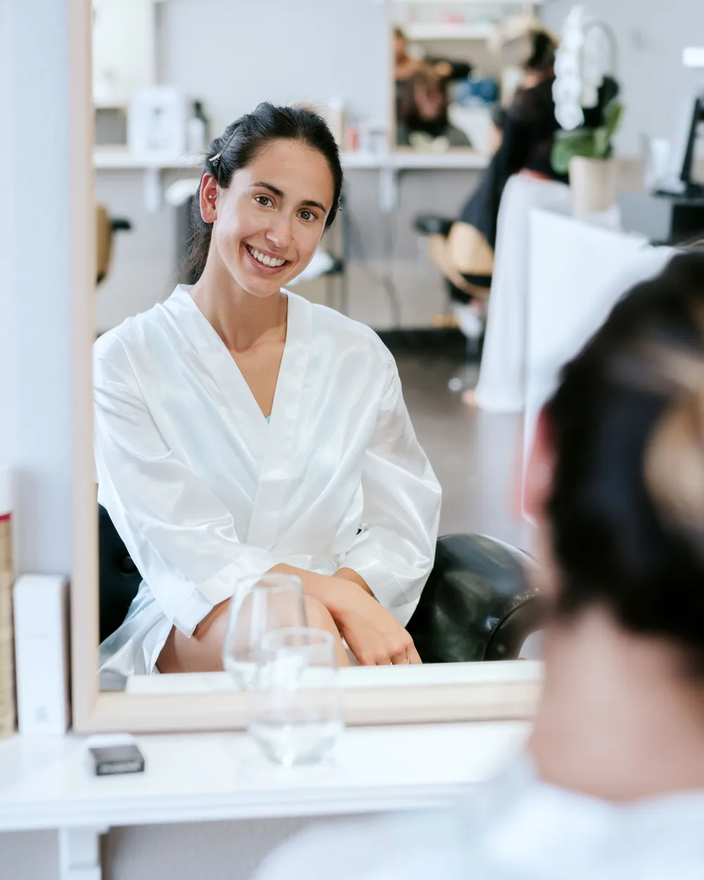 Klant bekijkt lachend haar nieuwe kapsel in de salonspiegel