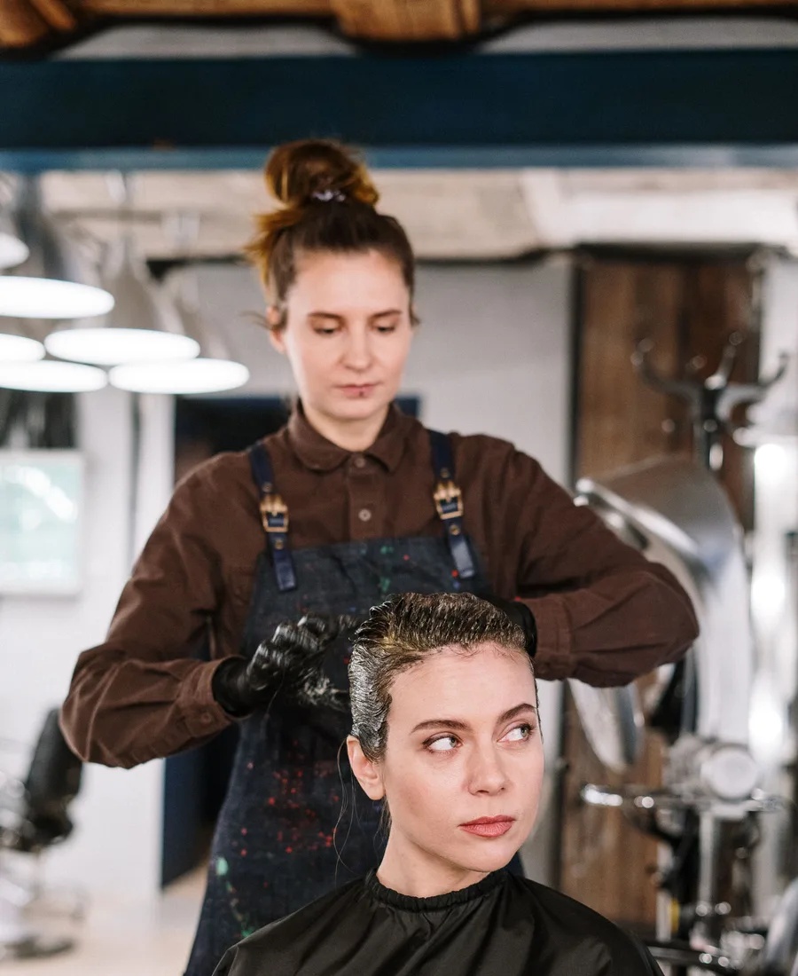Mara brengt geconcentreerd haarkleur aan bij een klant