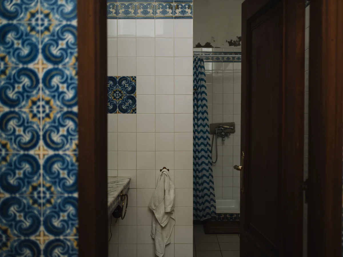 Gedateerde badkamer met blauw tegelwerk en douchegordijn