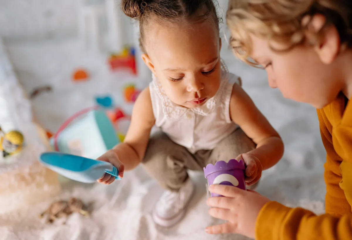 Pedagogisch medewerker troost liefdevol een jonge baby op schoot