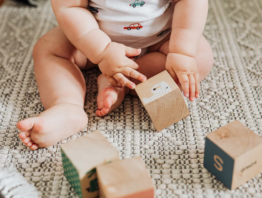Baby speelt met houten blokken op de grond