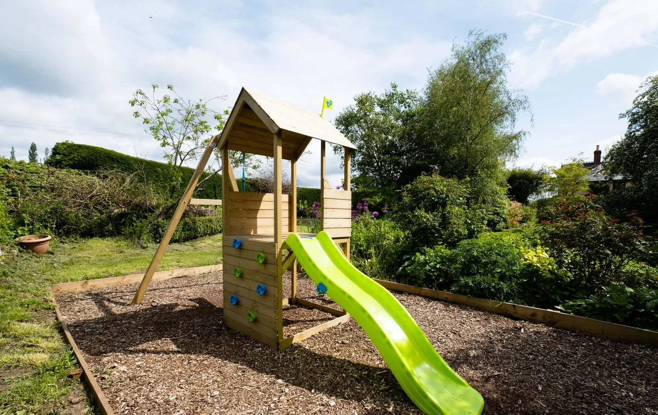 Houten speelhuis met glijbaan in een groene tuin