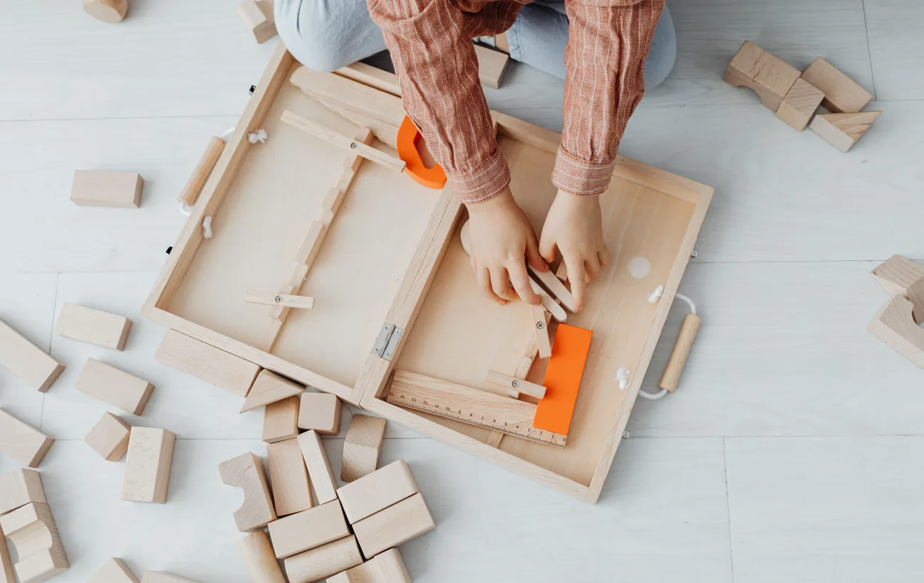 Kind bouwt met blank houten blokken uit een houten kist
