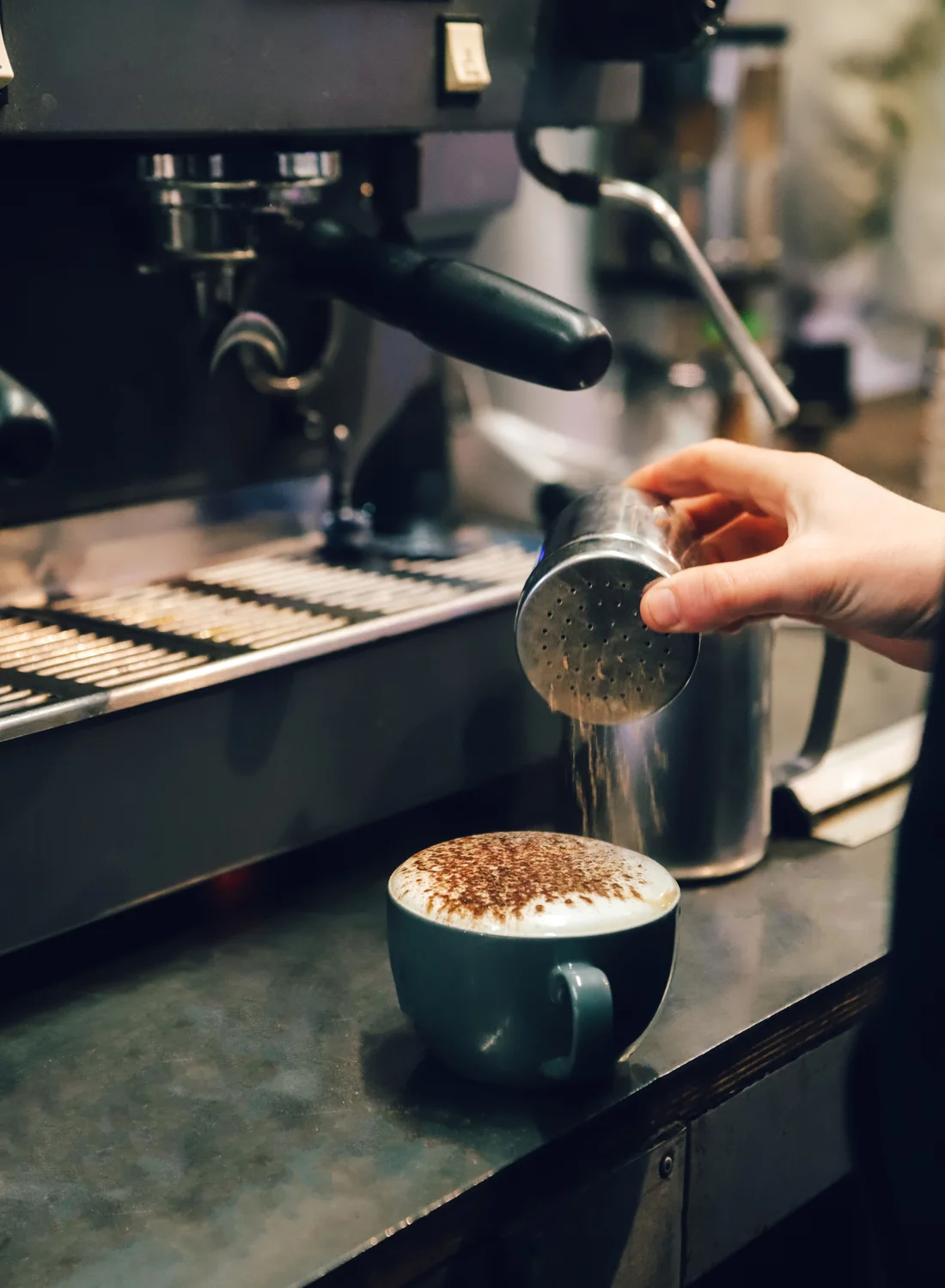 Cacao wordt over een cappuccino gestrooid