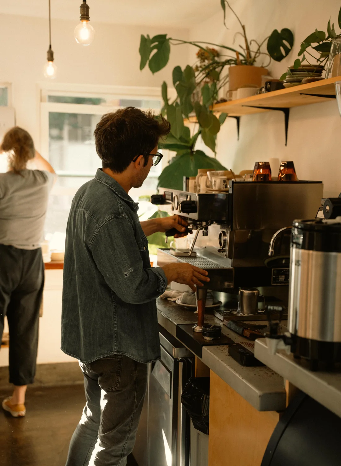 Barista aan het werk in de warme bar vol planten