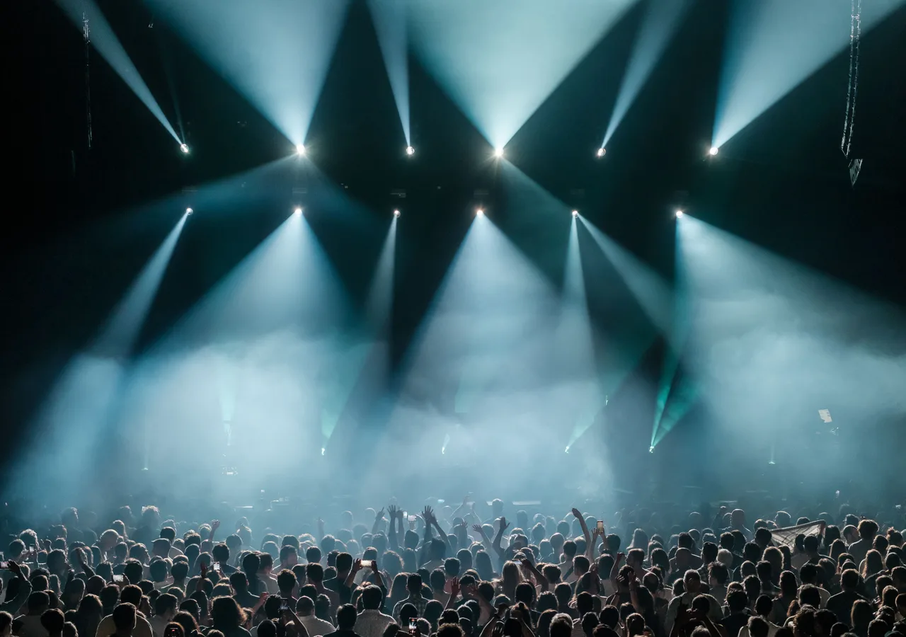 Volle festivalzaal met podiumlicht en handen in de lucht
