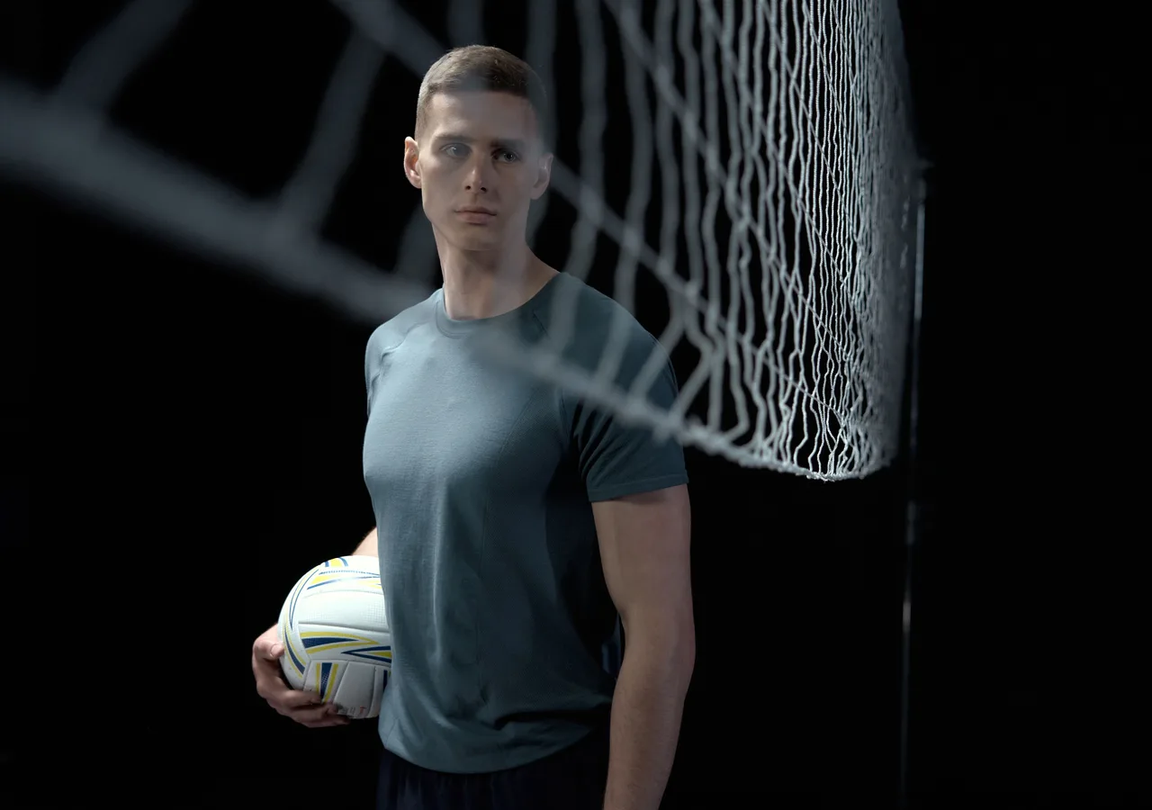 Sporter met bal in donker sportlicht, campagnebeeld voor een sportmerk