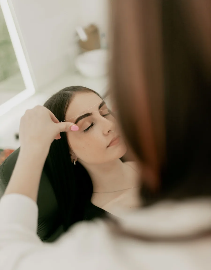 Wenkbrauwbehandeling met epileerdraad in de salon