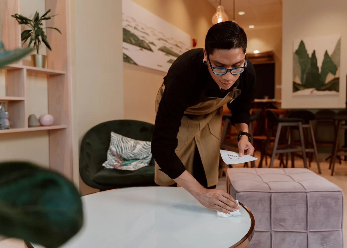 Medewerker neemt een tafel af in een caf&eacute;-interieur