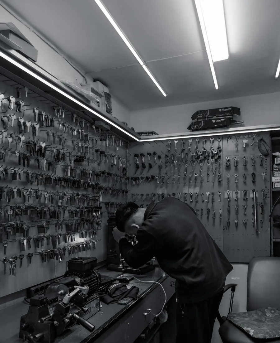 Slotenmaker aan het werk in het atelier met sleutelwand
