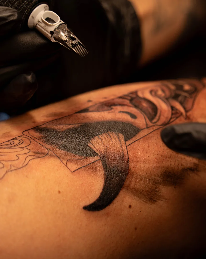 Close-up van een tattoo-machine die lijnen zet op een arm