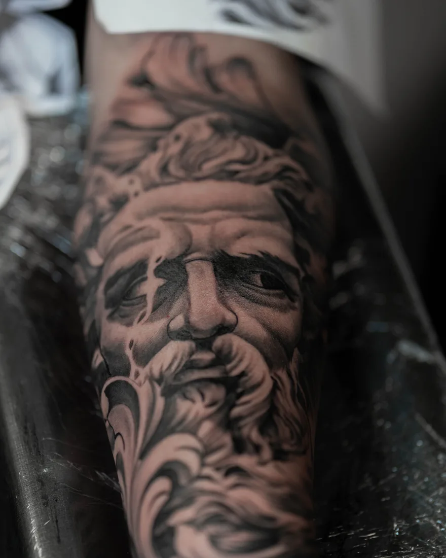Black-and-grey realisme tattoo van een klassiek beeldhouwwerk op een onderarm