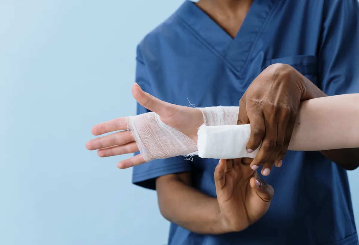 Wondverpleegkundige verzorgt beenwond met steriel hydrocolloïd verband