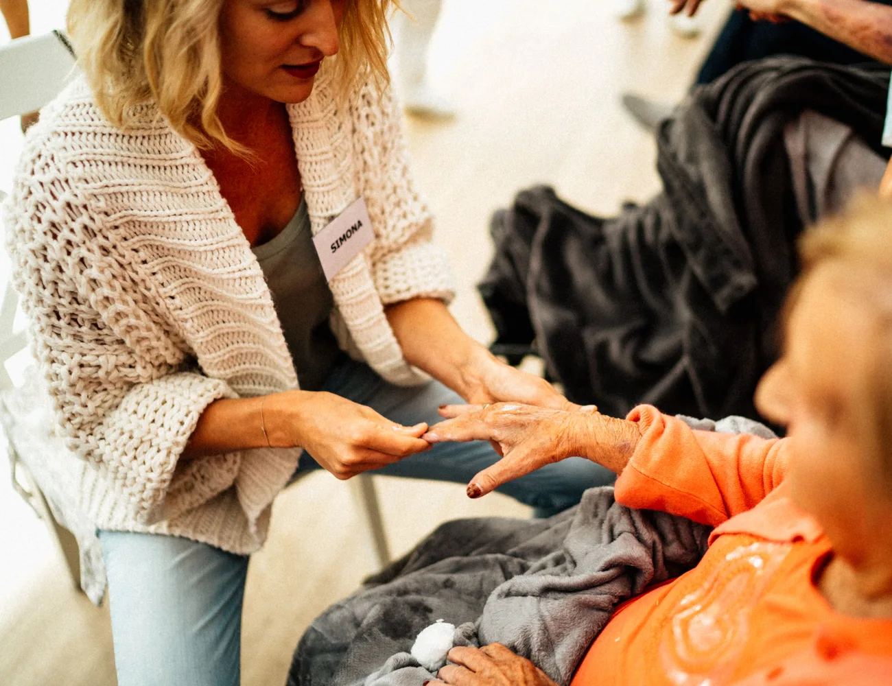 Zorgverlener wrijft voorzichtig crème op de hand van een oudere cliënt