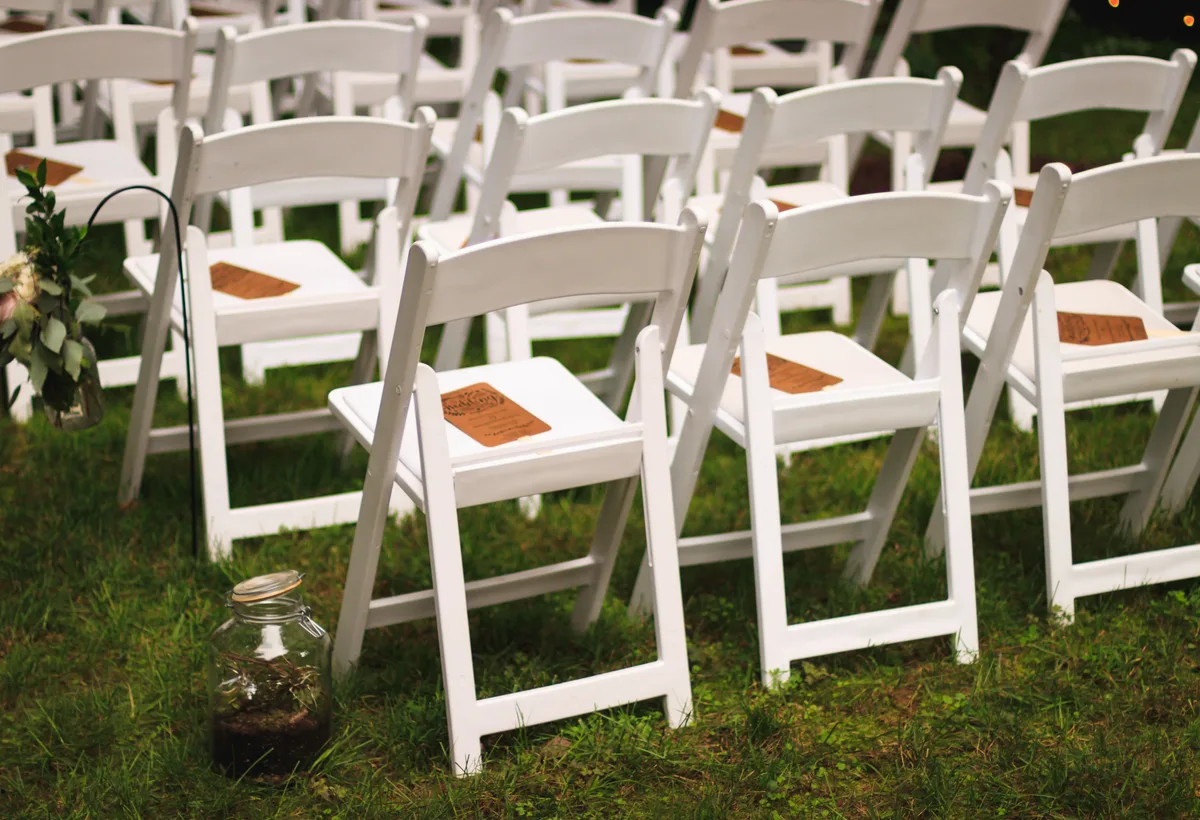 Romantische buitenceremonie met houten stoelen en bloemenprieel op een landgoed