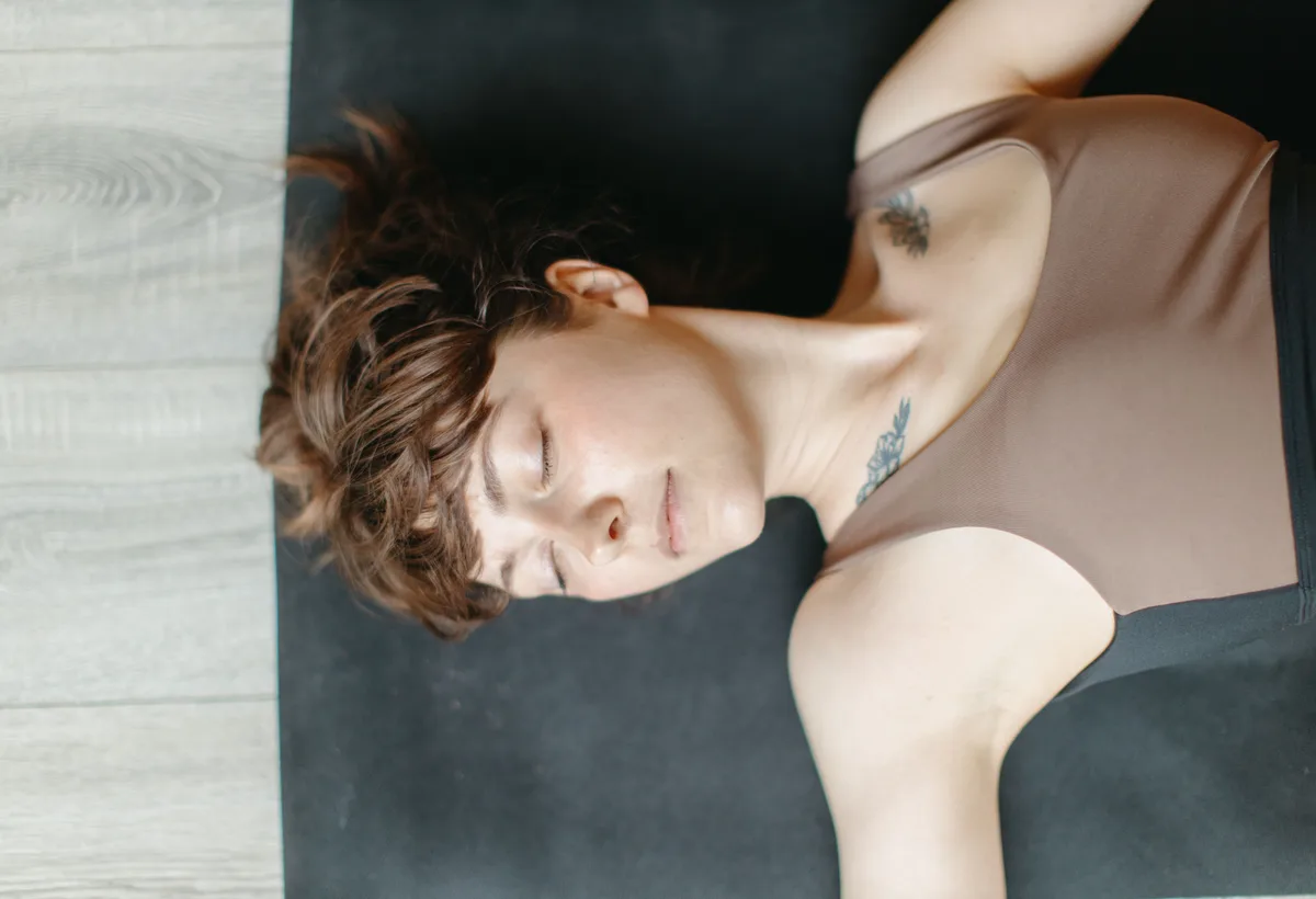Yogadocente in ontspannen Yin Yoga vlinderhouding op kurken yogamat