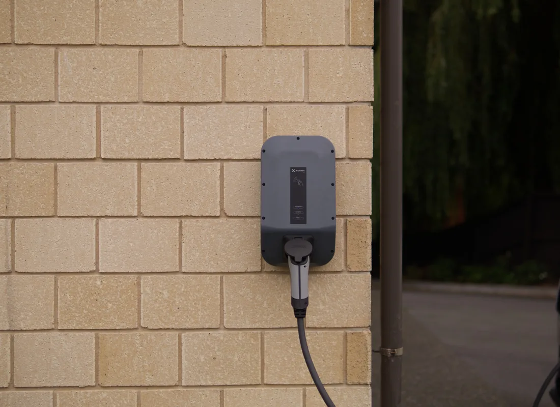 Wallbox-laadpunt aan een bakstenen muur bij een woning
