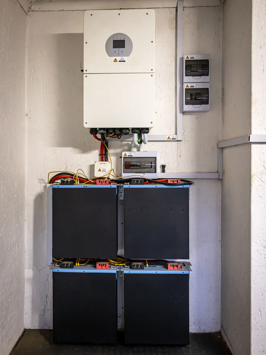 Omvormer met thuisbatterijen aan de muur in een berging